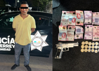 Man with eyes obscured standing beside a Monterrey police car; handgun and seized money laid out nearby.