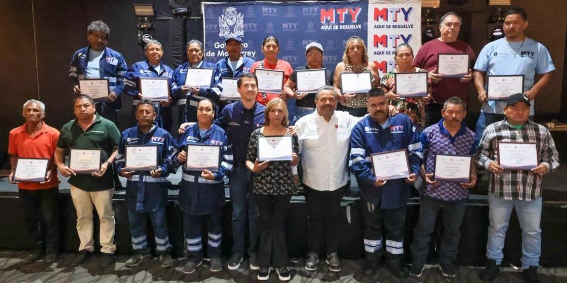 Group of people on a stage holding certificates at an awards ceremony, many in blue uniforms.