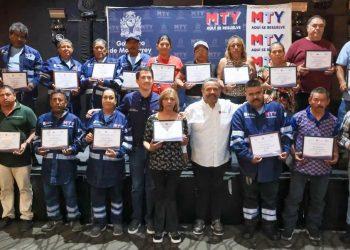 Group of people on a stage holding certificates at an awards ceremony, many in blue uniforms.